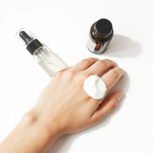 Lightweight oil-free moisturizer on the back of a hand with pump and dropper bottles in soft daylight