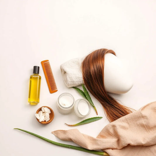 Natural hair care products arranged with comb and towel alongside a mannequin hair strand