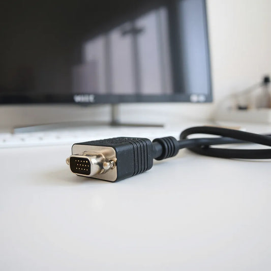 VGA male to male cable with two connectors, neatly arranged beside a monitor for screen setup