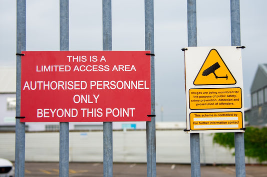 A red sign sitting on the side of a metal fence
