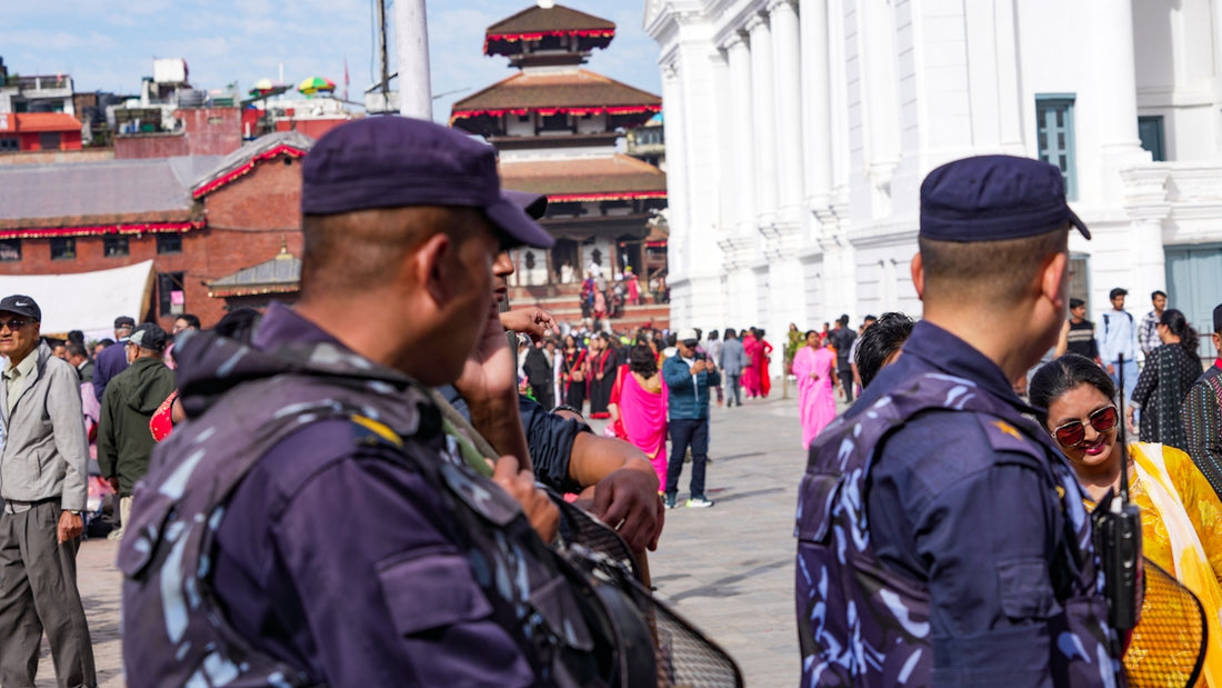 Two police officers stand guard in a crowded square.