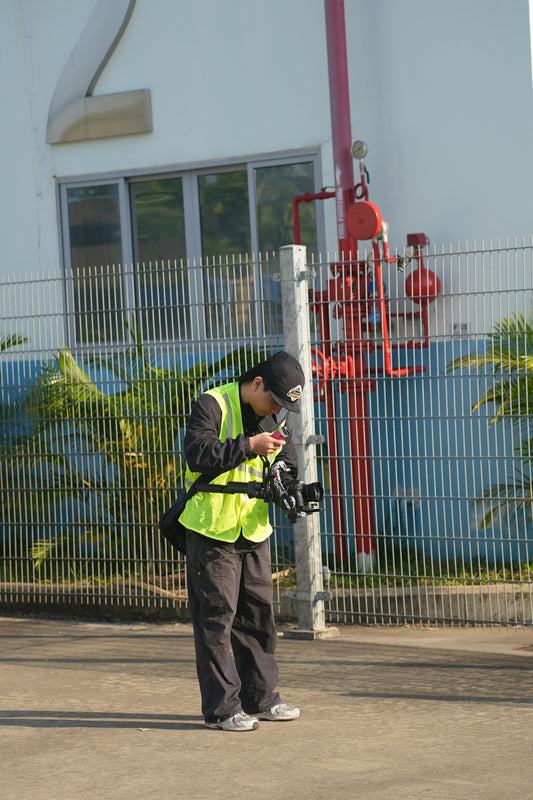 Man in safety vest using drone controller outdoors