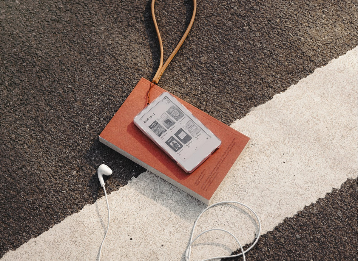 Boox Picco pocket e-reader held in one hand next to a phone