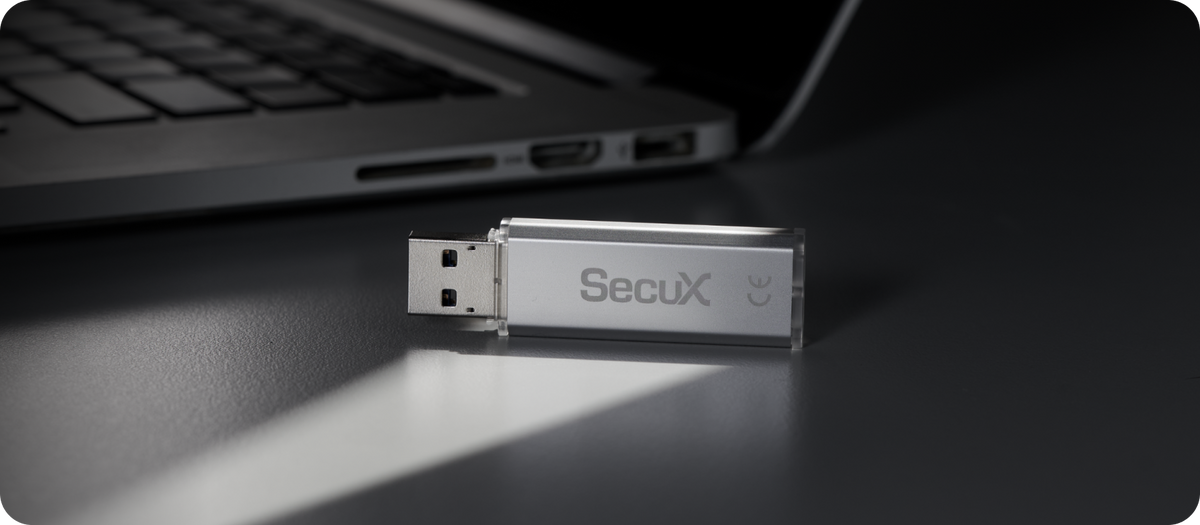 SecuX Forte USB flash drive lying beside a laptop, logo side up, official SecuX image
