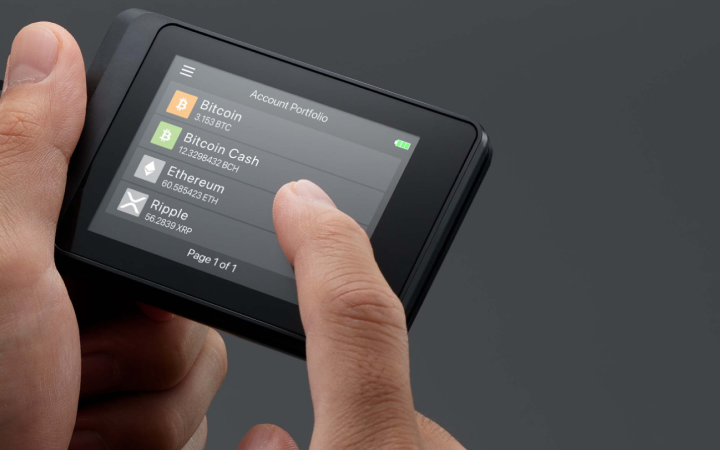 SecuX W10C-PLUS touchscreen showing the account portfolio while held in two hands