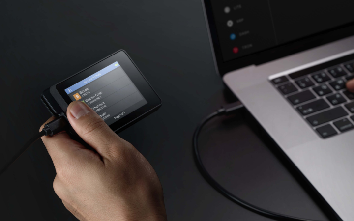 SecuX W10C-PLUS connected to a laptop by cable, with account balances on the wallet screen